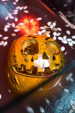 autumn holiday Halloween 2025 scary orange pumpkins drowning in water with bubbles and splatters in blood red light in the dark