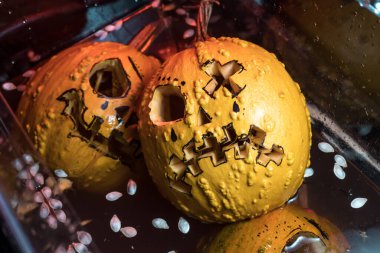 autumn holiday Halloween 2025 scary orange pumpkins drowning in water with bubbles and splatters in blood red light in the dark