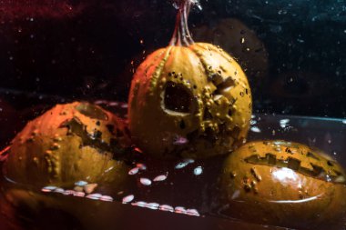 autumn holiday Halloween 2025 scary orange pumpkins drowning in water with bubbles and splatters in blood red light in the dark