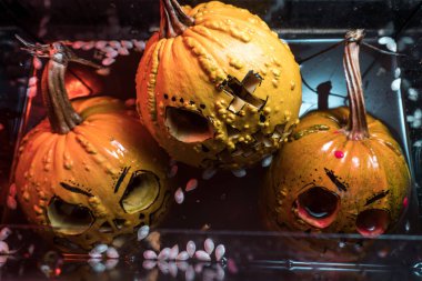 autumn holiday Halloween 2025 scary orange pumpkins drowning in water with bubbles and splatters in blood red light in the dark