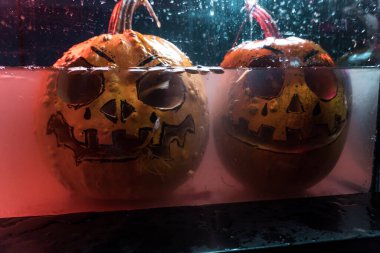 autumn holiday Halloween 2025 scary orange pumpkins drowning in water with bubbles and splatters in blood red light in the dark