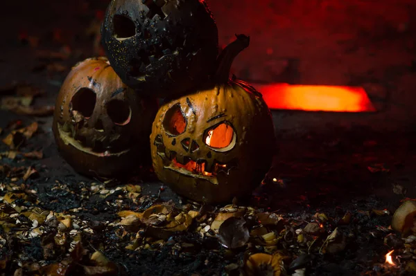 autumn holiday Halloween 2025 scary orange pumpkins burning in fire and smoke with blood red light in the dark