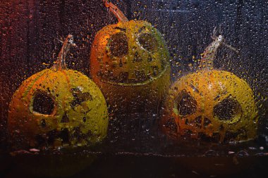 autumn holiday Halloween 2025 scary orange pumpkins drowning in water with bubbles and splatters in blood red light in the dark