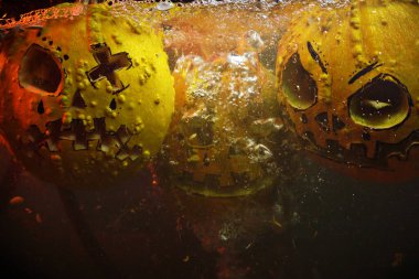 autumn holiday Halloween 2025 scary orange pumpkins drowning in water with bubbles and splatters in blood red light in the dark