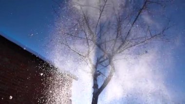 Kışın güneşli bir havada, karlı bir bahçede kar temizliği.