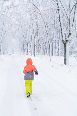 Kar üzerinde çalışan küçük bir çocuk. Çocuk çocuk ile yol boyunca çalışan 