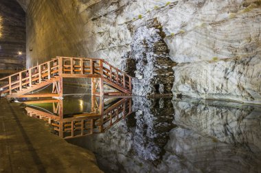 Wooden bridge reflection in underground salt mine lake clipart
