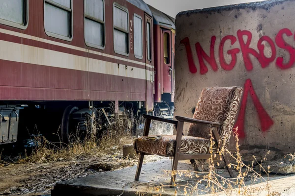 Oude vintage stoel in de buurt van rode trein wagon — Stockfoto