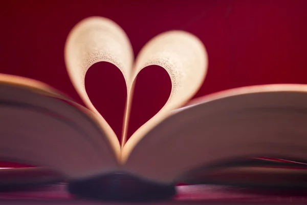 Blurry heart made from book pages over red background. Valentines theme. — Stock Photo, Image