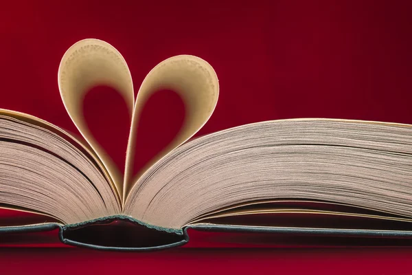 Corazón borroso hecho de páginas de libros sobre fondo rojo. Tema San Valentín . — Foto de Stock