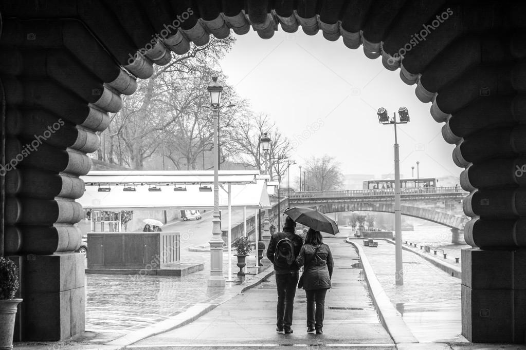 Lovers couple walking on the Sein quai in Paris in a rainy day