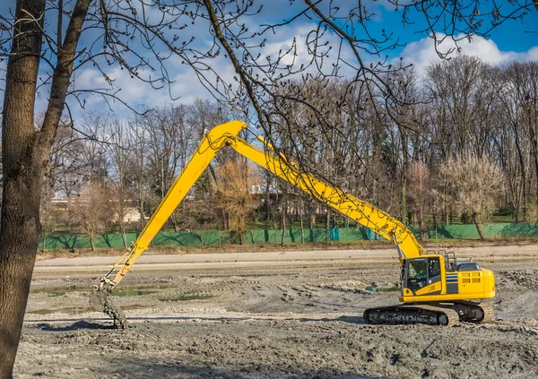 Excavadora amarilla que realiza servicios de limpieza y mantenimiento de lagos bajo autoridad municipal en un parque — Foto de Stock