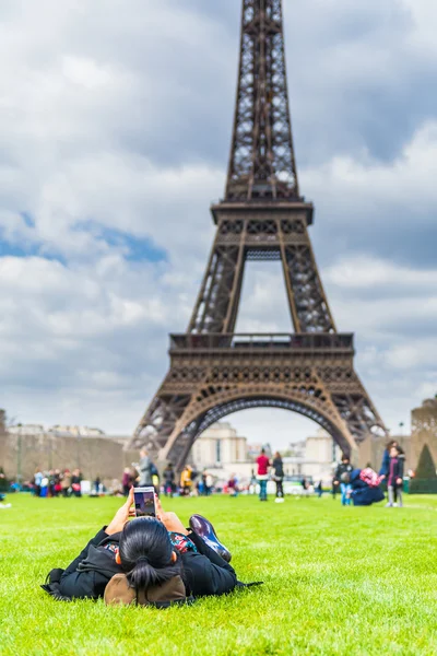 Молода жінка покладення gras перед Ейфелева вежа — стокове фото