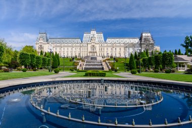 IASI, ROMANIA - 23 MAY 2015: Iasi Cultural Palace being restaurated with a beautiful green park on a sunny spring day with dramatic sky on background clipart