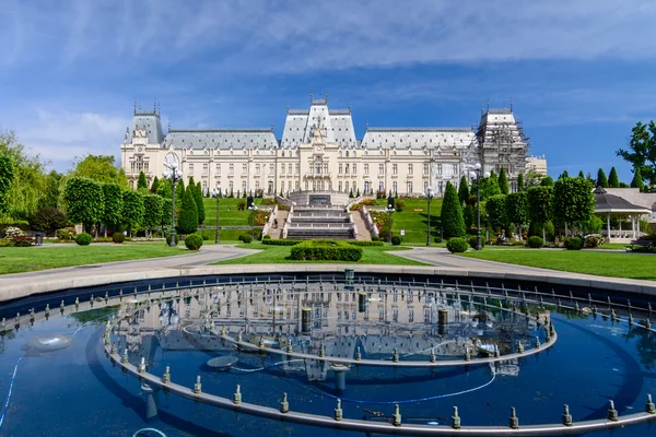 IASI, RUMANIA - 23 DE MAYO DE 2015: El Palacio Cultural de Iasi está siendo restaurado con un hermoso parque verde en un soleado día de primavera con un cielo dramático en el fondo — Foto de Stock