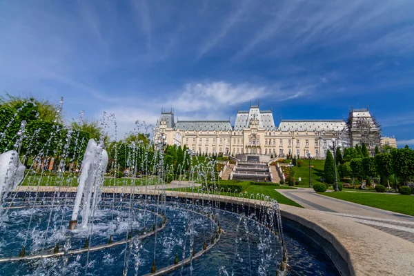 IASI, RUMANIA - 23 DE MAYO DE 2015: El Palacio Cultural de Iasi está siendo restaurado con un hermoso parque verde en un soleado día de primavera con un cielo dramático en el fondo — Foto de Stock