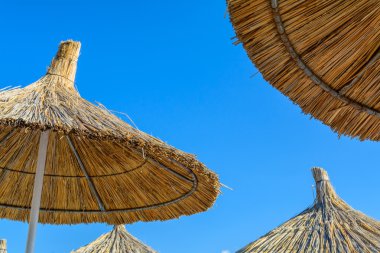 Mavi gökyüzü arka plan üzerinde bir güneşli yaz günü Plajda şemsiye
