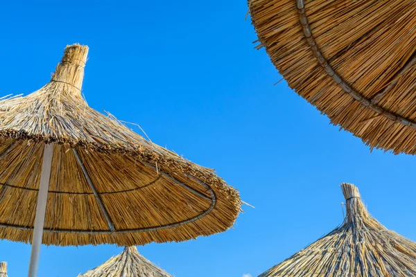 Parasol en la playa en un soleado día de verano sobre un fondo de cielo azul —  Fotos de Stock