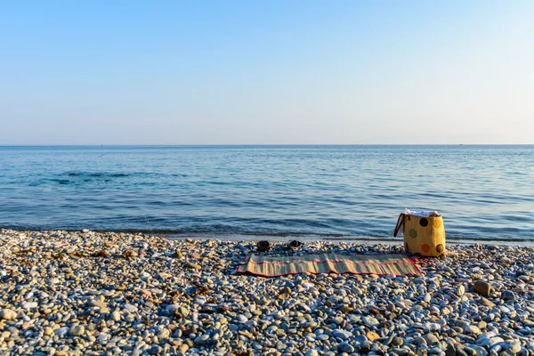 Fundo de viagem com um saco amarelo, na areia de uma bela praia em um dia ensolarado de verão — Fotografia de Stock