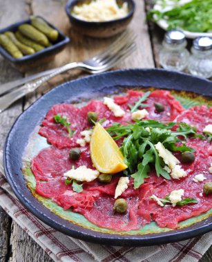 Carpaccio kapari, parmesan, roka, limon ve zeytin yağı ile sığır eti.