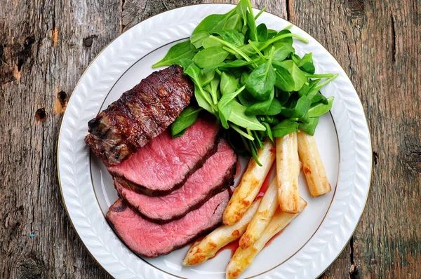 Medium rare steak with asparagus and baby spinach. — Stock Photo, Image