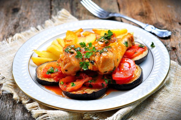 Braised chicken in white wine with eggplant, tomato and french fries.