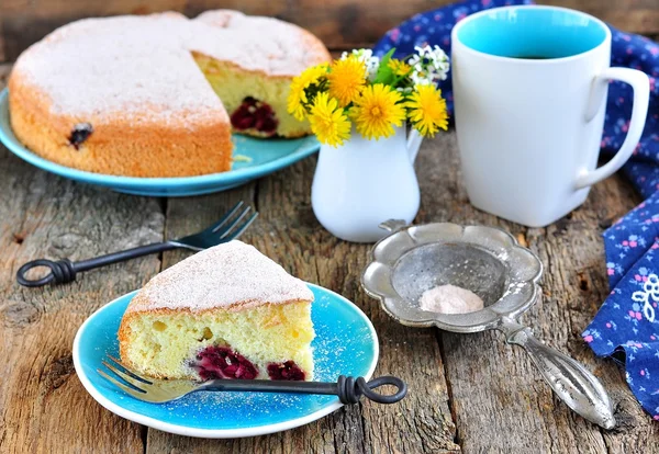 Sponge cake with a cherry on old wooden background. — Stock Photo, Image