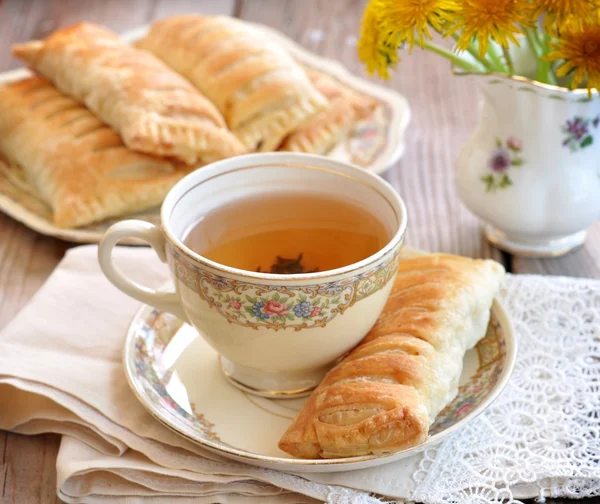 Pasteles de hojaldre con una taza de té en una mesa de madera. Estilo vintage . — Foto de Stock