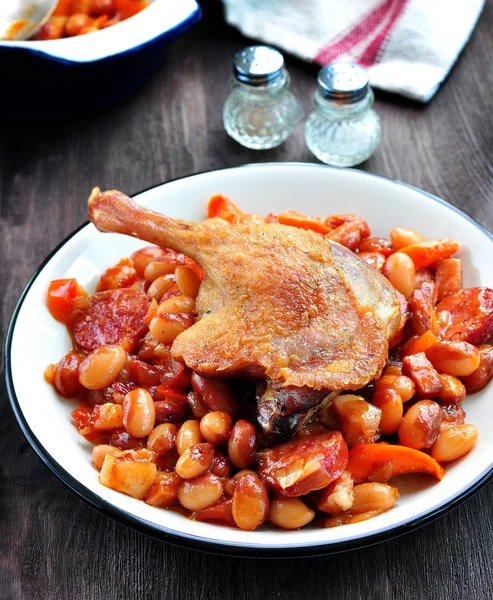 Patata de pato asado con frijoles casoulet, cebolla, tocino, zanahorias con salchicha de cerdo frito — Foto de Stock