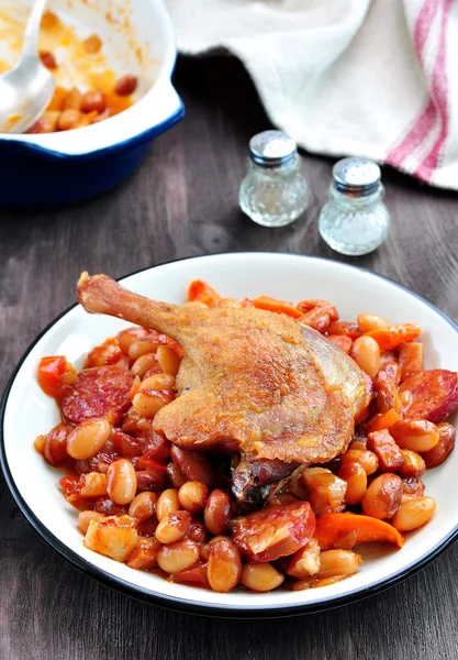 Patata de pato asado con frijoles casoulet, cebolla, tocino, zanahorias con salchicha de cerdo frito — Foto de Stock