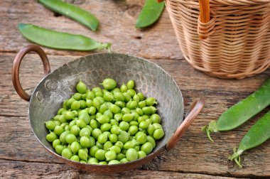 Ahşap arka plan üzerinde bir sepet içinde taze organik yeşil bezelye.