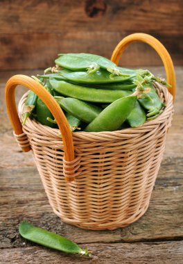 Ahşap arka plan üzerinde bir sepet içinde taze organik yeşil bezelye.