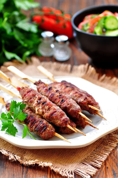 Zelfgemaakte kebab op spiesjes met een salade van tomaat en komkommer. — Stockfoto