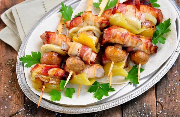 Varkensvlees verpakt in spek brochettes gegrild met uien, champignons en paprika. — Stockfoto