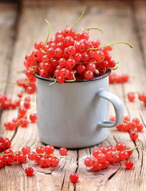 Eski ahşap masa üzerinde bir fincan taze organik kırmızı kuş üzümü.