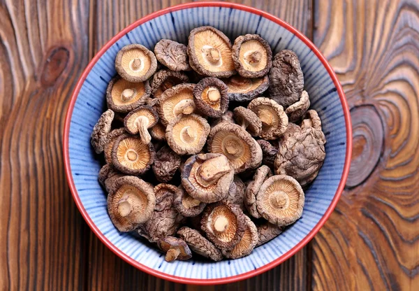 Dried shiitake mushrooms on a wooden background.