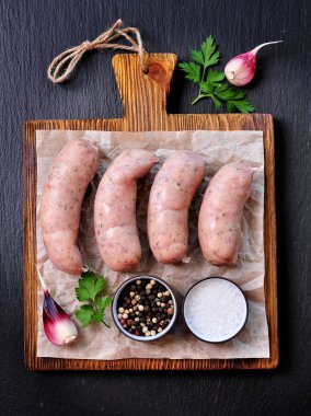 sarımsak ve maydanoz bir ahşap kesme tahtası üzerinde çiğ tavuk sosis