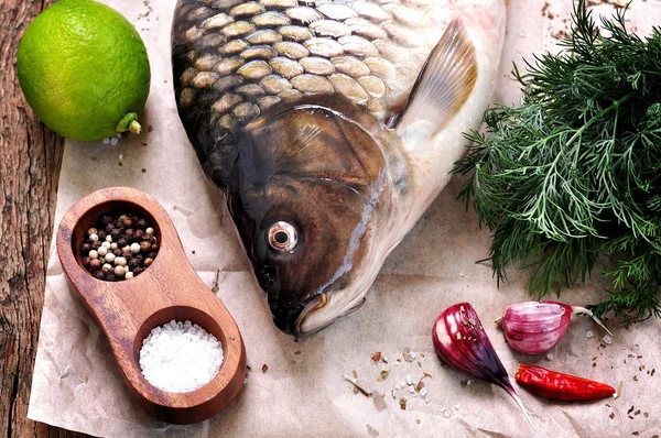 Frischer roher Karpfenfisch mit Limette, Dill und Knoblauch auf altem Holzgrund. — Stockfoto