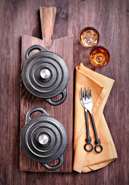 De kleine gietijzeren pan met vorken en glazen op een snijplank — Stockfoto