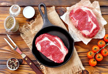 ahşap arka plan üzerinde ham antrikot biftek ile dökme demir tava.