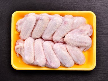 Kara tahta üzerinde çiğ tavuk kanadı.