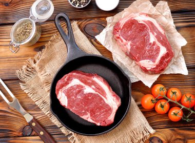 ahşap arka plan üzerinde ham antrikot biftek ile dökme demir tava.