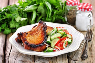 Salata, domates, salatalık, soğan, maydanoz ve zeytinyağı ile ızgara domuz pirzolası.