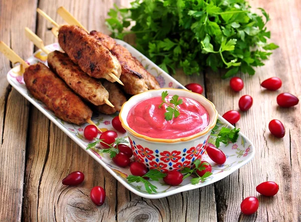 Homemade sauce dogberry with meat kebabs on wooden skewers. — Stock Photo, Image