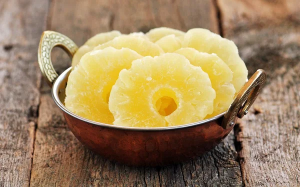 Eski ahşap arka plan bakır tabakta şekerlenmiş ananas parçaları. — Stok fotoğraf