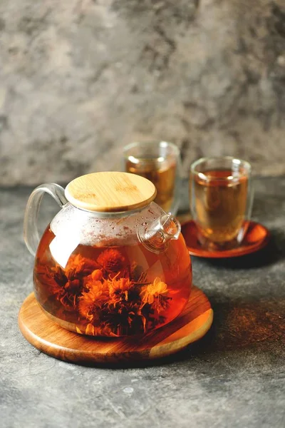 Glass teapot and cup with blooming tea flower