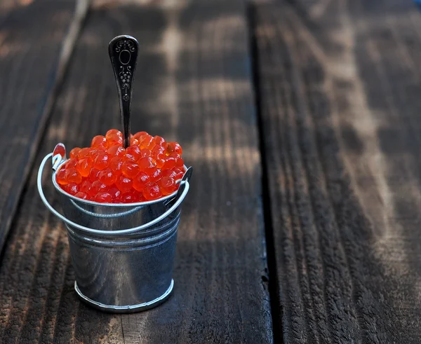나무 테이블에 빨간 캐 비어의 양동이 — 스톡 사진