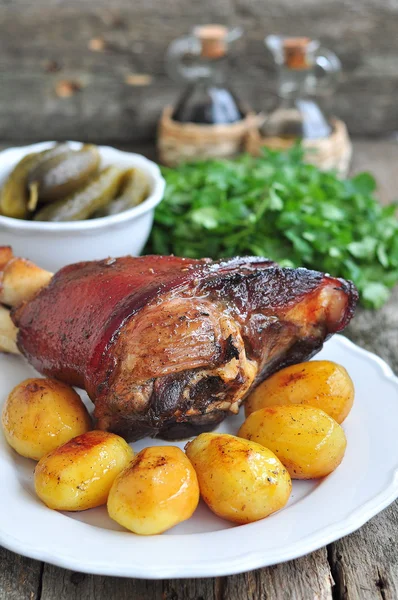 Poignée de porc rôti bavarois appétissante sur la planche à découper avec la pomme de terre cuite au four — Photo
