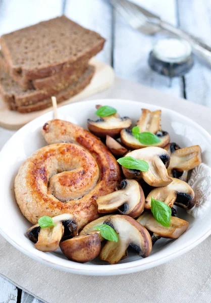 Chicken sausages with the fried mushrooms and basil on a white wooden table — Stock Photo, Image