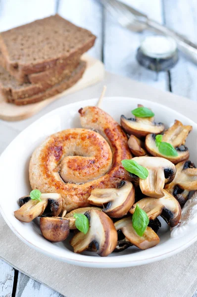 Chicken sausages with the fried mushrooms and basil on a white wooden table — Stock Photo, Image